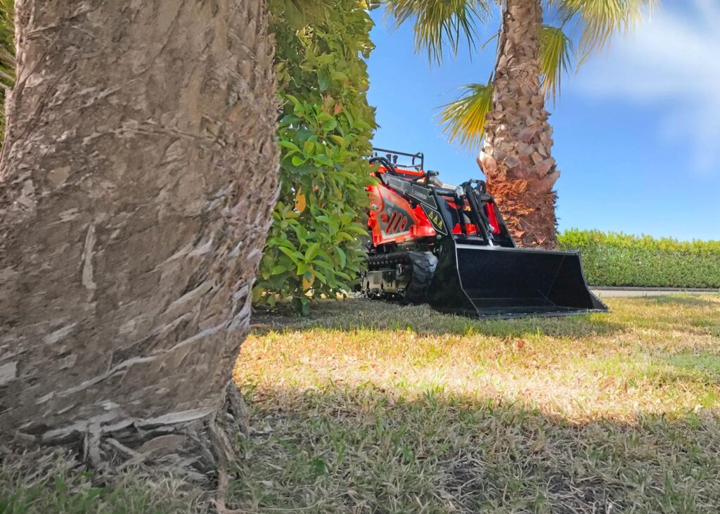 Mini truck loader cingolato Cormidi al lavoro in un’area verde durante attività di movimentazione terreno.