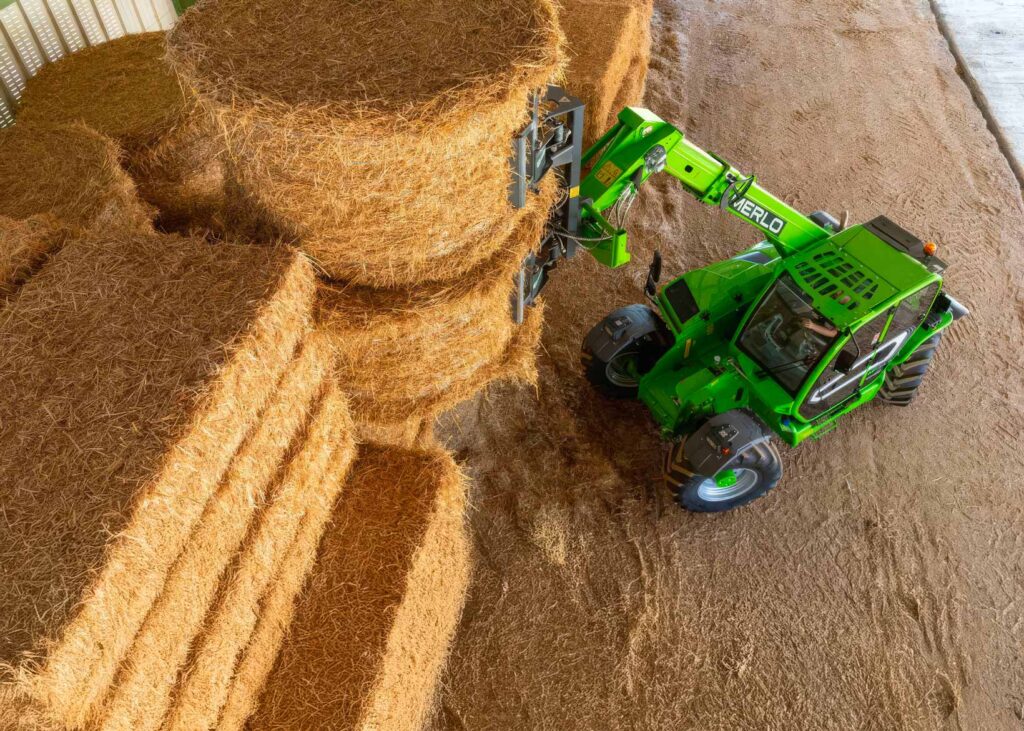 Sollevatore telescopico Merlo movimenta balle di paglia all’interno di un capannone agricolo.