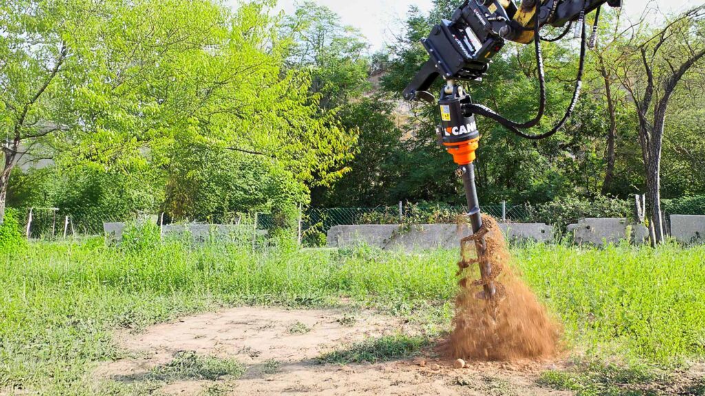Trivella Cangini ATC in azione su escavatore durante operazione di perforazione del terreno.