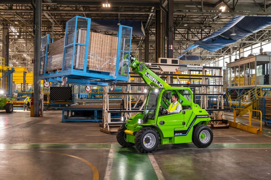 Sollevatore telescopico Merlo movimenta materiali all’interno di un ambiente industriale.