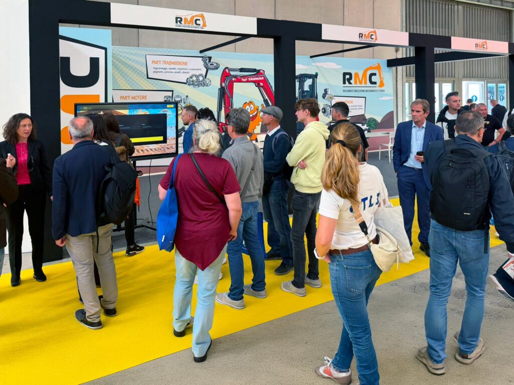 Visitatori riuniti davanti alla ruota motrice della fortuna presso lo stand RMC durante il SaMoTer 2026.