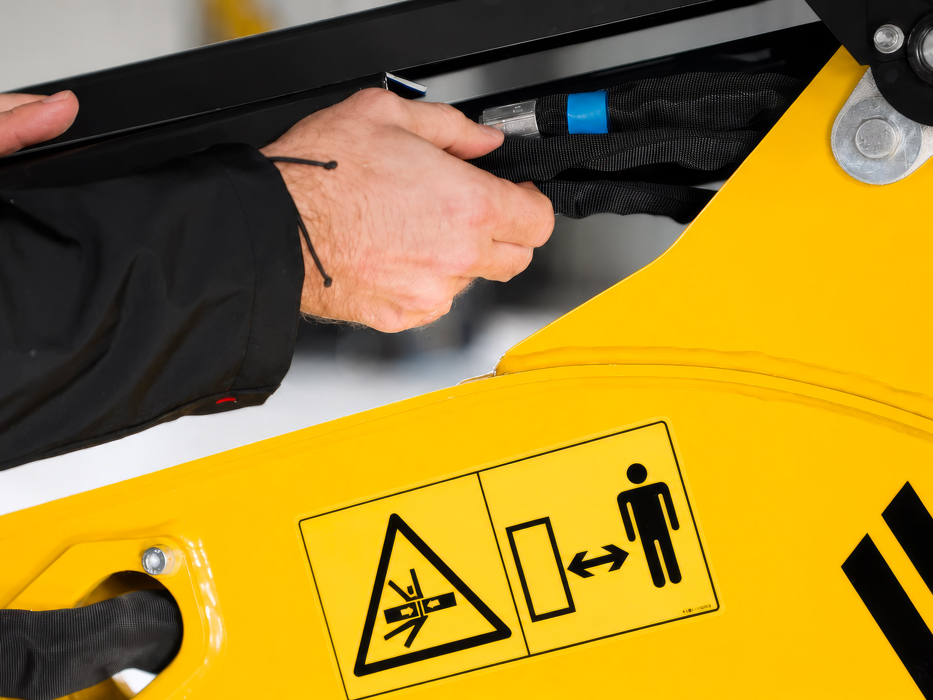 Tecnico durante il controllo di componenti e cablaggi di un escavatore nell'ambito delle attività di manutenzione preventiva.