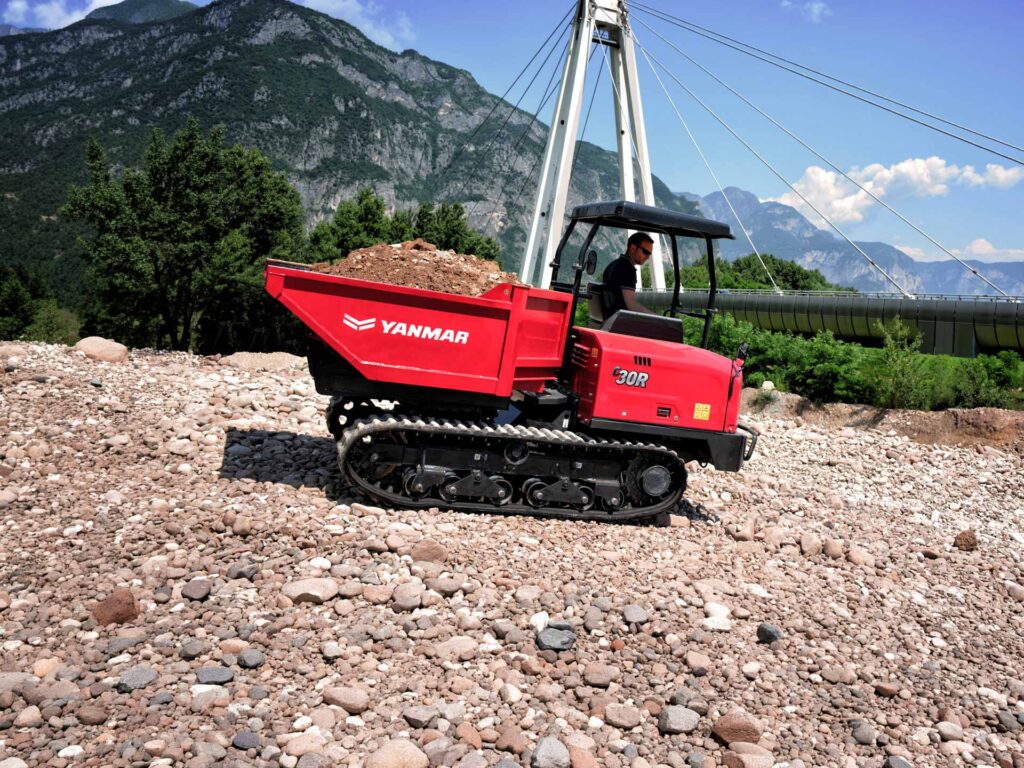Dumper cingolato Yanmar C30R trasporta materiale su un terreno sassoso in un cantiere all'aperto.