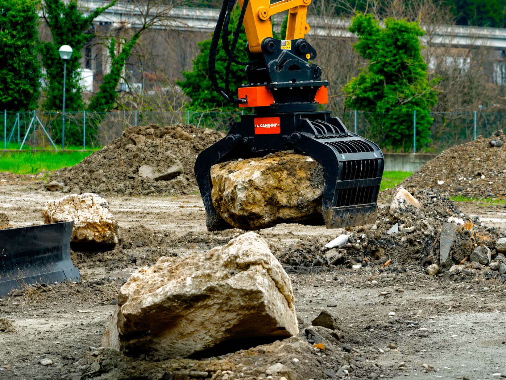 Pinza selezionatrice Cangini con rotazione idraulica a 360° durante la movimentazione di un grande masso in cantiere.
