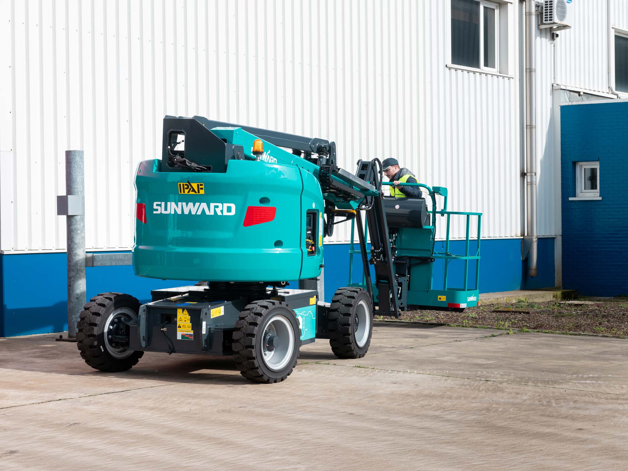 Piattaforma aerea elettrica Sunward SWA 16JE con braccio articolato ripiegato e operatore sulla cesta.